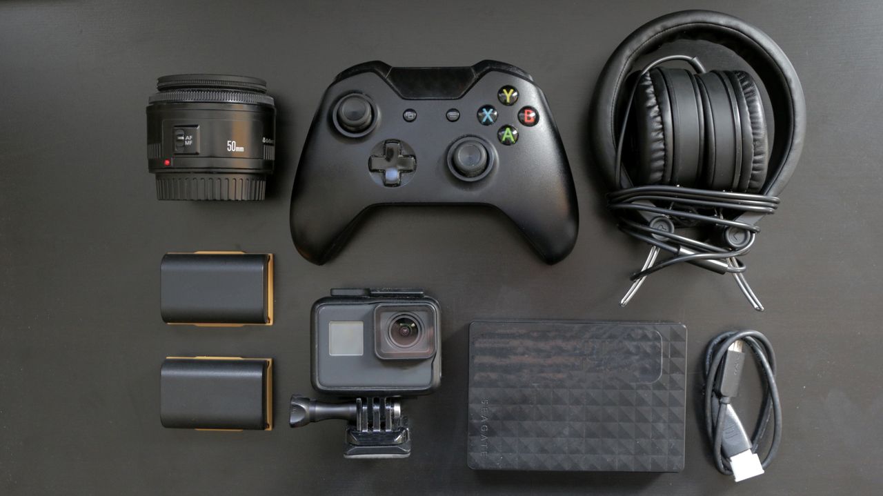 Top view of various gaming and tech gadgets, including a controller and headphones.